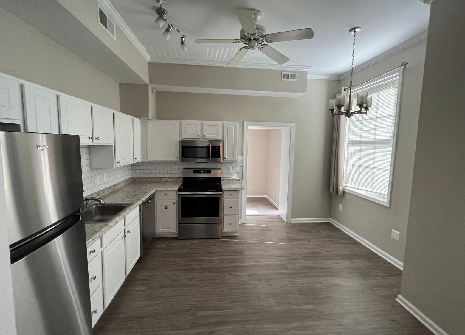 A renovated kitchen with white cabinetry, stainless steel appliances, subway-tile backsplash, and high ceilings
